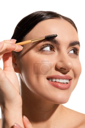 close up of happy young woman styling eyebrows with brush and gel isolated on white 