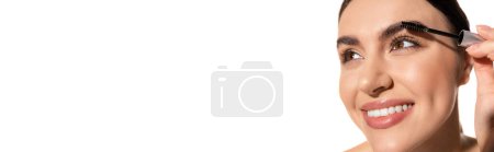 Téléchargez les photos : Gros plan de jeune femme heureuse tenant brosse et sourcils coiffants avec gel isolé sur blanc, bannière - en image libre de droit