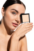 brunette woman covering eye while holding neutral beige face powder isolated on white  Stickers #642938234