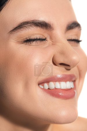 Nahaufnahme der glücklichen Frau mit geschlossenen Augen und natürlichem makellosen Make-up isoliert auf weiß 