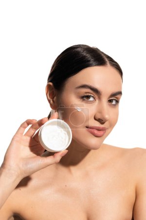 brünette Frau hält Glas mit pflegender Gesichtscreme isoliert auf weiß 