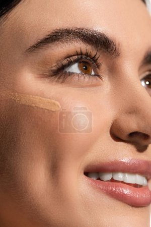 Téléchargez les photos : Maquillage fond de teint tache sur le visage d'une jeune femme heureuse à la peau douce - en image libre de droit