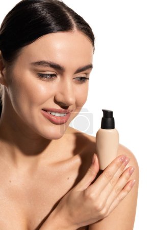 cheerful young woman holding bottle with liquid face foundation isolated on white 