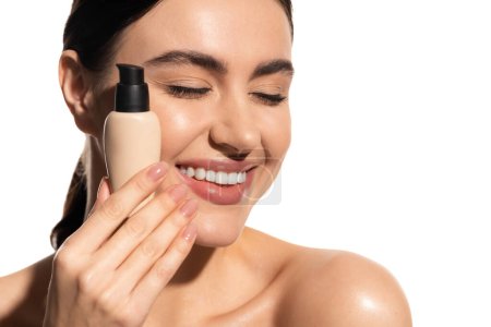 pleased woman with closed eyes holding bottle with liquid makeup foundation isolated on white