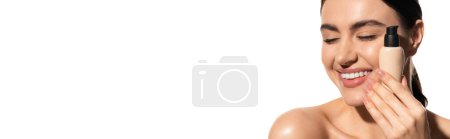 pleased woman holding bottle with liquid makeup foundation isolated on white, banner 