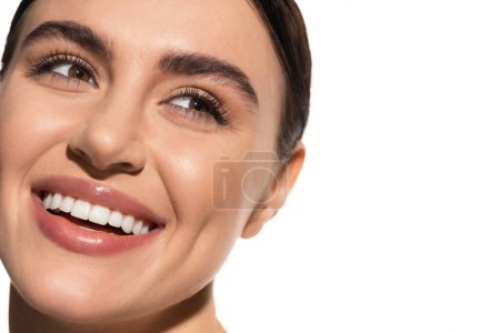 Nahaufnahme einer zufriedenen jungen Frau mit makellosem Make-up, die isoliert auf Weiß lächelt 
