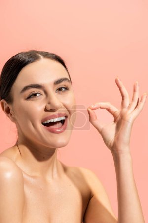 Foto de Mujer alegre con la boca abierta mostrando signo ok aislado en rosa - Imagen libre de derechos
