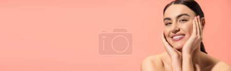 Photo for Charming young woman with bare shoulders looking at camera while smiling isolated on pink, banner - Royalty Free Image