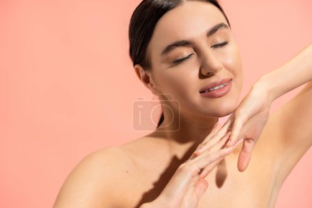 Charmante Frau mit geballten Händen und geschlossenen Augen posiert isoliert auf rosa 