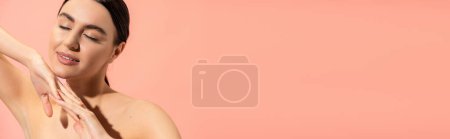 charming woman with clenched hands and closed eyes posing isolated on pink, banner 