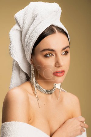 young woman in luxurious jewelry posing with towel on head on beige  Stickers 642941290