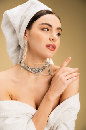 Foto de Elegant young woman with makeup and luxurious jewelry looking away on beige background - Imagen libre de derechos