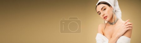 Photo for Sensual woman with makeup and white towel on head touching bare shoulder on beige background, banner - Royalty Free Image