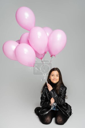 Photo for Stylish kid in leather jacket holding pink balloons on grey background - Royalty Free Image