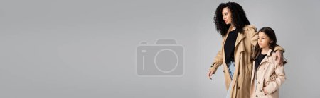 Téléchargez les photos : Femme tendance étreignant fille en trench coat isolé sur gris, bannière - en image libre de droit