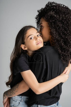 Preteen kid in black t-shirt hugging curly parent isolated on grey