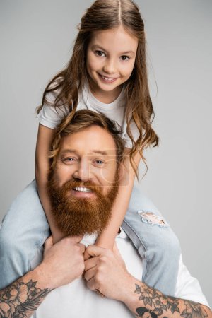 Porträt des Mädchens sitzt auf den Schultern des fröhlichen Vaters isoliert auf grau 