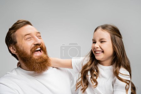 Excited kid and father in white t-shirts laughing isolated on grey 