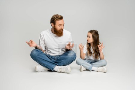 Photo for Kid and bearded dad doing gyan mudra while sitting on grey background - Royalty Free Image