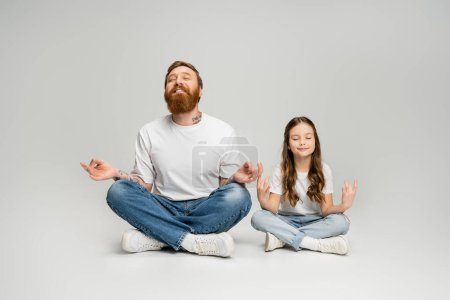 Smiling man and daughter doing gyan mudra while meditating on grey background