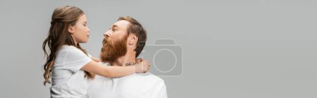 Photo for Preteen child pouting lips and hugging tattooed dad isolated on grey, banner - Royalty Free Image