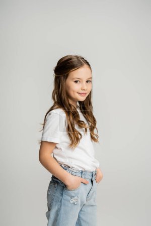 Carefree preteen kid posing and looking at camera isolated on grey  