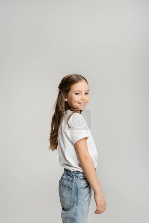 Overjoyed preteen girl in casual clothes looking at camera isolated on grey  