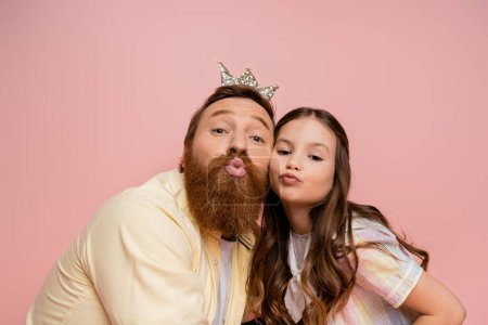 Photo for Preteen girl pouting lips near father with crown headband isolated on pink - Royalty Free Image