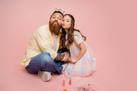 Photo for Bearded man with crown headband pouting lips near daughter and decorative cosmetics on pink background - Royalty Free Image
