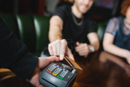 Verschwommene Ansicht eines Mannes, der in Bar mit Kreditkarte bezahlt 