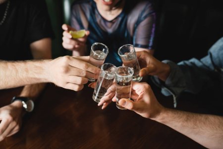 Vista recortada de amigos interracial sosteniendo vasos de tequila con sal en el bar 