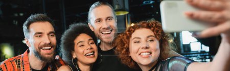 Téléchargez les photos : Jeune rousse femme prendre selfie avec des amis interracial dans le bar, bannière - en image libre de droit