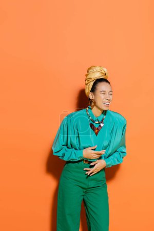 Stilvolles afrikanisch-amerikanisches Model lacht auf orangefarbenem Hintergrund 