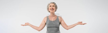 Photo for Satisfied senior woman with grey hair looking up and gesturing isolated on grey, banner - Royalty Free Image