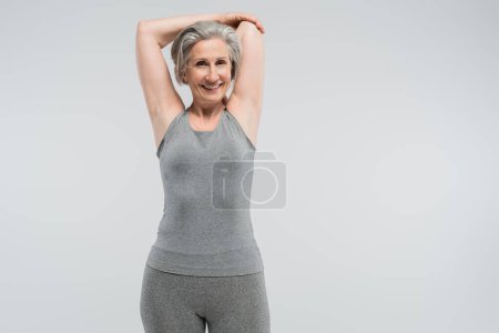 Photo for Joyful grandmother in sportswear working out and smiling isolated on grey - Royalty Free Image