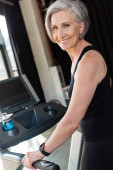 happy senior woman with grey hair exercising on treadmill in gym  Sweatshirt #648884784