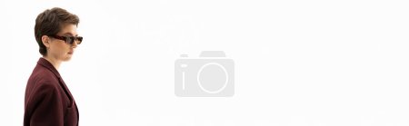 Téléchargez les photos : Jeune femme brune en blazer marron bordeaux et lunettes de soleil élégantes isolées sur blanc, bannière - en image libre de droit