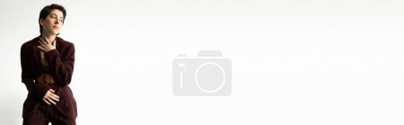 Téléchargez les photos : Femme élégante et coûteuse en costume marron bordeaux regardant loin sur fond blanc, bannière - en image libre de droit