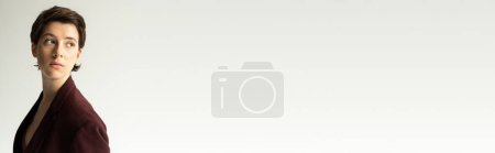 Téléchargez les photos : Jeune et rêveuse femme en veste marron bordeaux regardant loin isolé sur gris, bannière - en image libre de droit