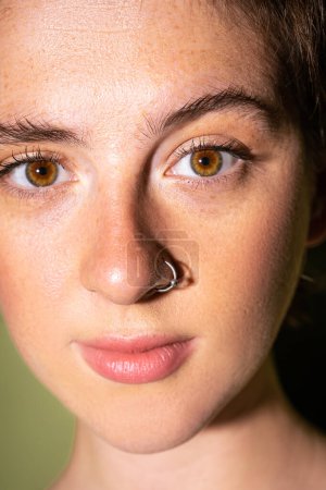 close up portrait of young woman with freckles and nose piercing