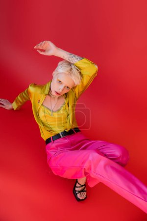 Foto de Mujer albina con el pelo rubio posando con la mano tatuada levantada en rosa carmín - Imagen libre de derechos