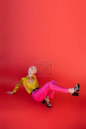 in voller Länge Albino-Frau in Sandalen und trendigem Outfit posiert auf karminrosa 