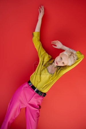 Téléchargez les photos : Femme albinos aux cheveux blonds et la main tatouée posant sur carmin rose - en image libre de droit