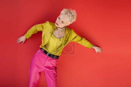Photo for Blonde woman with blonde hair and tattooed hand posing in trendy clothes on carmine pink - Royalty Free Image