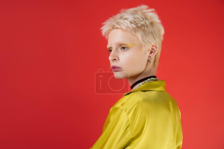 Porträt einer blonden Albino-Frau mit hellem Eyeliner auf karminrosa Hintergrund 