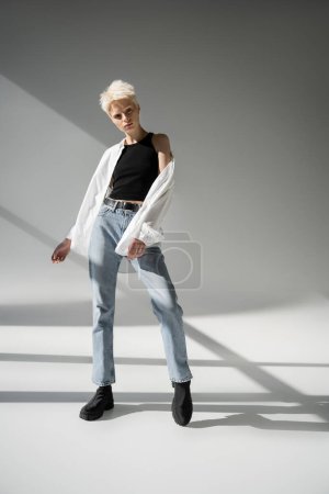 Photo for Full length of albino woman in black tank top and white shirt posing on grey background with shadows - Royalty Free Image