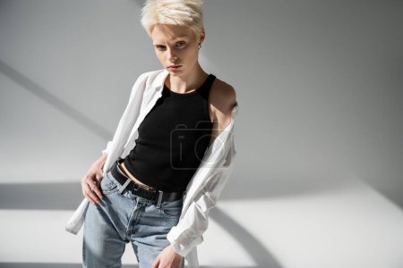 albino woman in black tank top and white shirt posing on grey background 