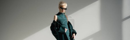 pretty woman with fair-skin posing in dress and coat on grey background, banner 