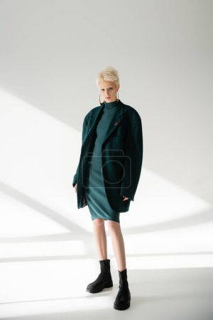 Photo for Full length of young albino woman with fair-skin posing in green dress and coat on grey background - Royalty Free Image