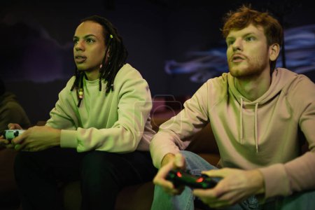 Photo for KYIV, UKRAINE - FEBRUARY 13, 2023: Multiracial man playing video game with young friend in gaming club - Royalty Free Image